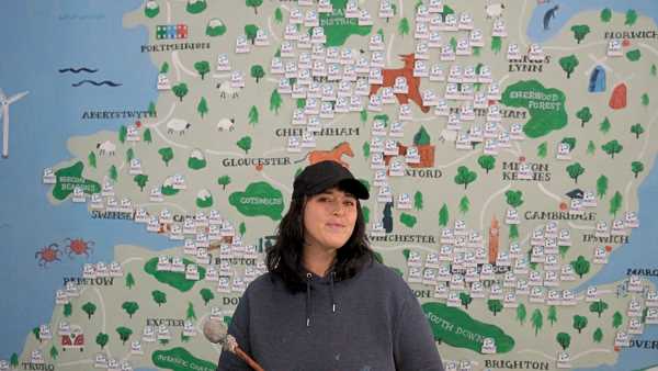 Image shows Abi standing in front of a mural of the British Isles